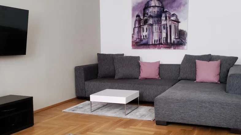 Gemütliches Wohnzimmer mit modernem Sofa, Fernseher und Kunstwerk an der Wand.