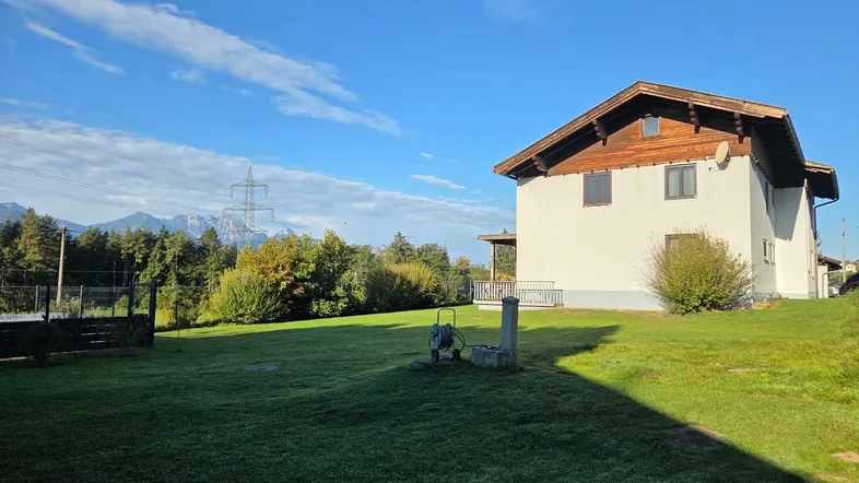 Großzügiger Gartenbereich mit Blick auf die Berge und das Einfamilienhaus im ländlichen Stil.