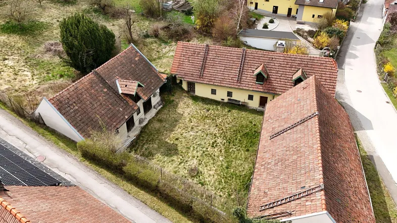 Luftaufnahme eines Anwesens mit mehreren Gebäuden, roten Ziegeldächern und einer großen Grünfläche.