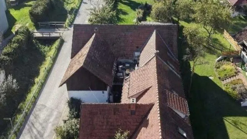 Luftaufnahme des Anwesens mit roten Ziegeldächern und umliegender grüner Landschaft.