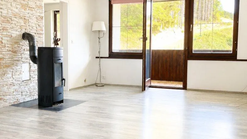 Helles Wohnzimmer mit modernem Kaminofen, Steinwandakzent und hellem Laminatboden.