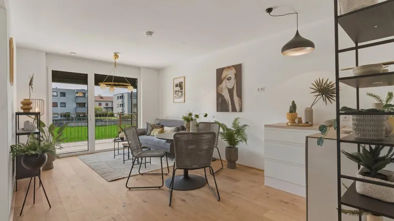 Helles, offenes Wohn-Esszimmer mit Holzboden, modernen Möbeln und Zugang zum Balkon.
