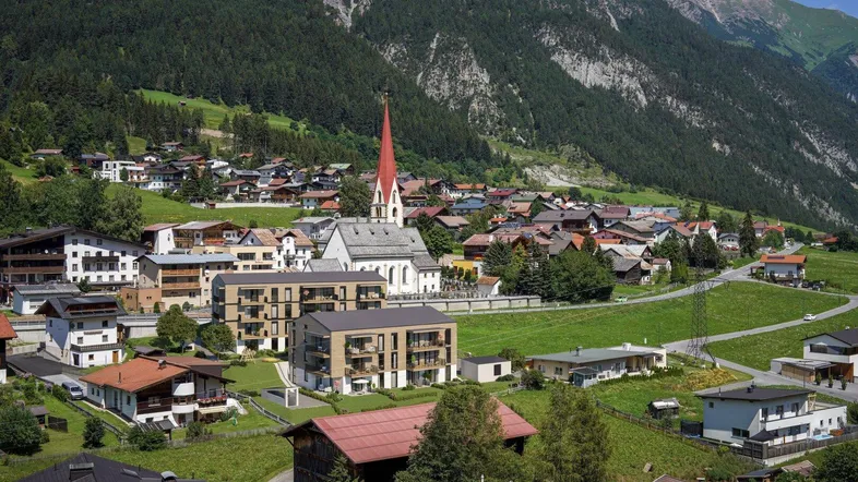 Panoramablick auf ein malerisches Dorf in den Bergen mit traditionellen und modernen Gebäuden.