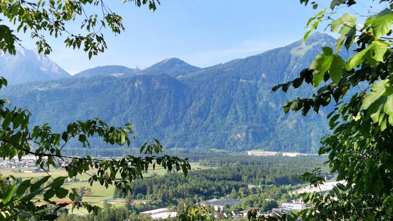 Panoramablick auf die majestätischen Berge und das grüne Tal mit einer kleinen Siedlung.