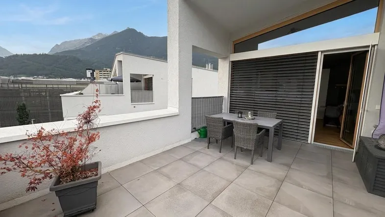 Geräumige Terrasse mit Esstisch und Stühlen, umgeben von einer beeindruckenden Bergkulisse.