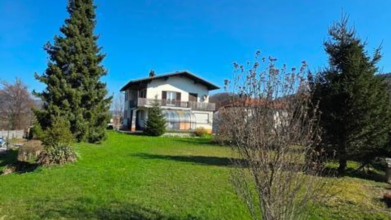 Großzügiger Gartenbereich mit Rasenfläche und Blick auf das Wohnhaus unter blauem Himmel.