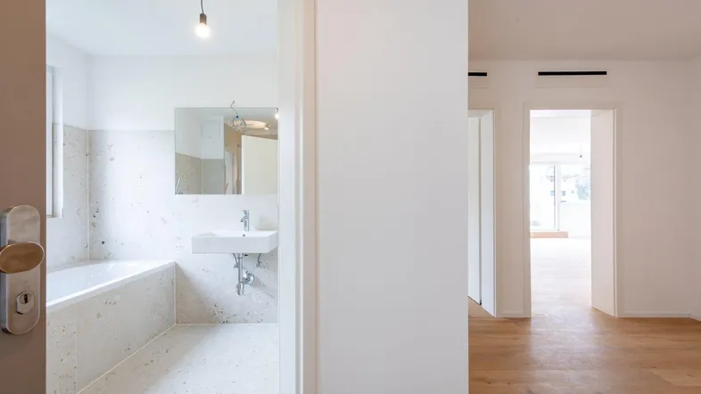 Eingangsbereich zu einem modernen Badezimmer mit Badewanne und hellen Fliesen.