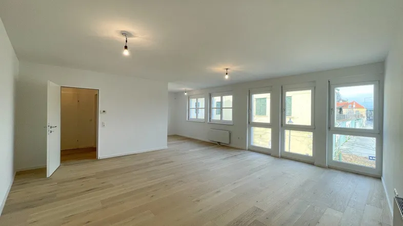 Heller, leerer Raum mit Holzboden und vielen Fenstern, bereit zur individuellen Gestaltung.