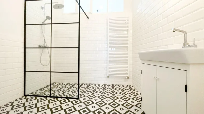 Modernes Badezimmer mit begehbarer Dusche, geometrischen Fliesen und Handtuchheizkörper.