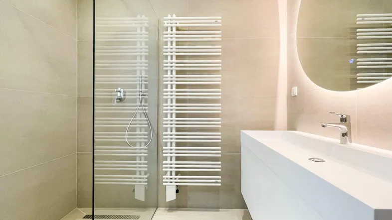 Modernes Badezimmer mit begehbarer Dusche, schwebendem Waschtisch und beheiztem Handtuchhalter.