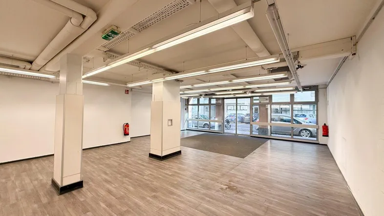 Eingangsbereich des Gewerberaums mit breiter Glasfront und hellem Laminatboden.