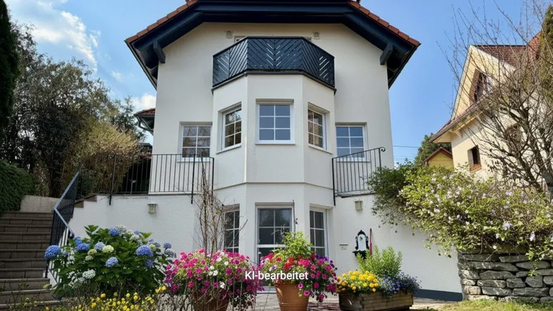 Attraktives Einfamilienhaus mit gepflegtem Vorgarten und blühenden Pflanzen unter blauem Himmel.