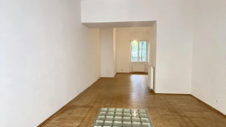 Heller, leerer Wohnbereich mit Parkettboden und einem integrierten Glasbaustein-Element im Boden.