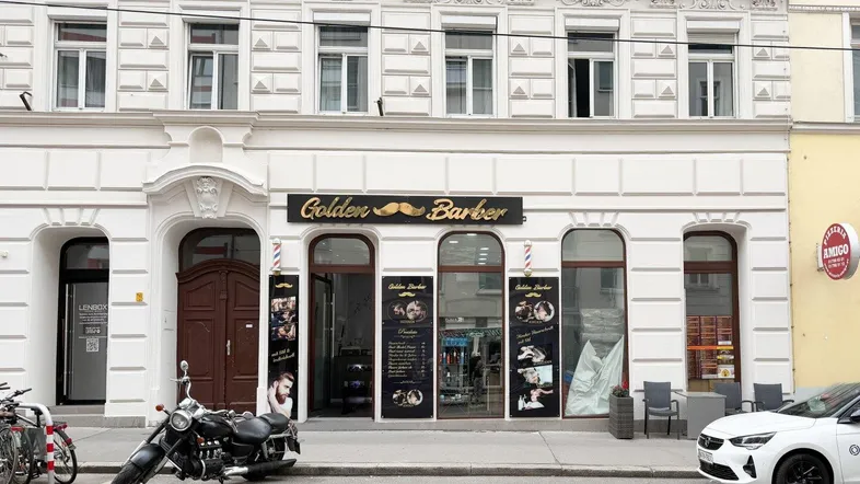 Fassade eines historischen Gebäudes mit Stuckverzierungen und einem Friseursalon im Erdgeschoss.