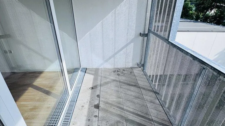 Heller Balkon mit Fliesenboden und Blick auf die umliegende grüne Landschaft.