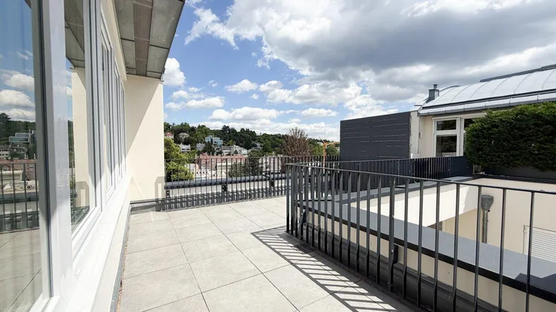 Weitläufige Terrasse mit Fliesenboden und Geländer, bietet einen Panoramablick über die Stadt und Hügel.