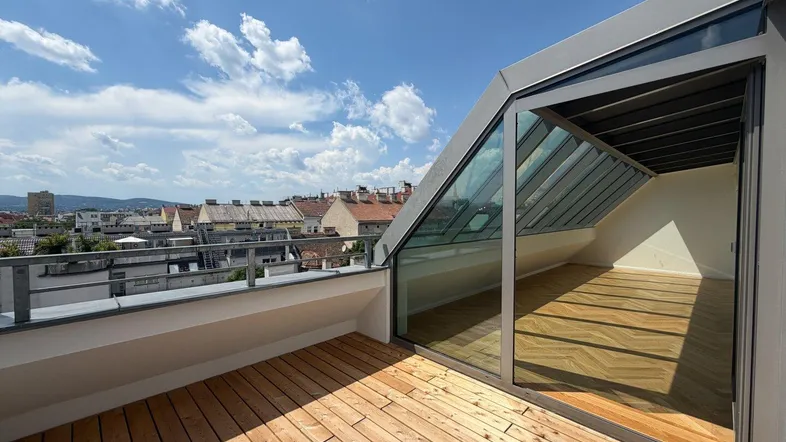 Geräumige Dachterrasse mit Holzboden, Glasfassade und weitem Blick über die Stadt.