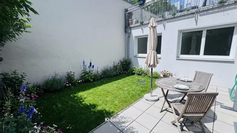 Gepflegte Terrasse mit Gartenmöbeln, Sonnenschirm und einem kleinen Rasenbereich mit Blumenbeeten.