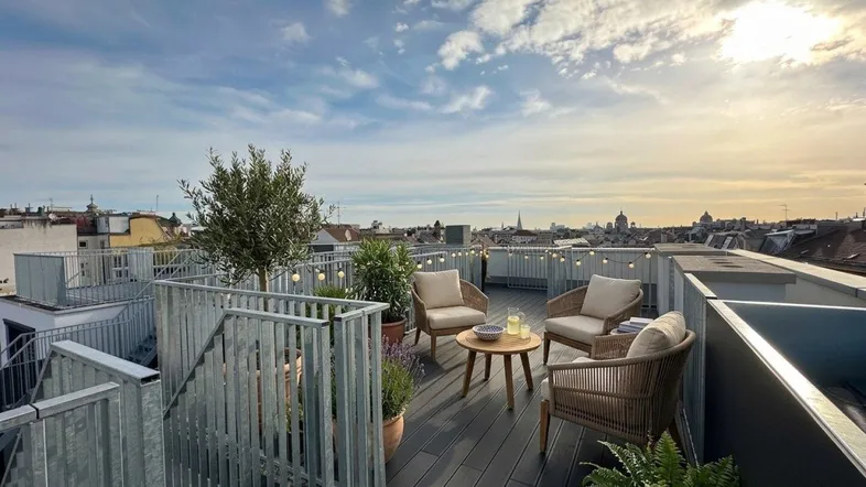 Geräumige Dachterrasse mit Sitzgelegenheiten, Pflanzen und weitem Blick über die Stadt.
