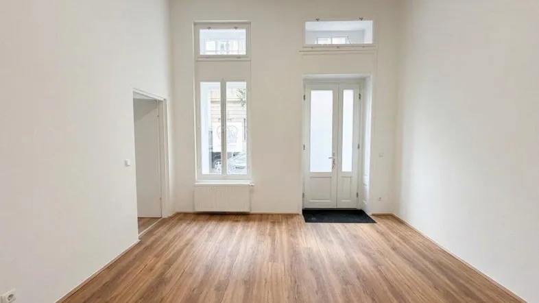 Heller, leerer Raum mit hohen Decken und Holzboden, ideal für Wohn- oder Geschäftszwecke.