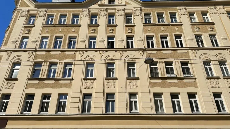 Klassische Fassade eines Altbaus mit symmetrischen Fenstern und dekorativen Elementen.