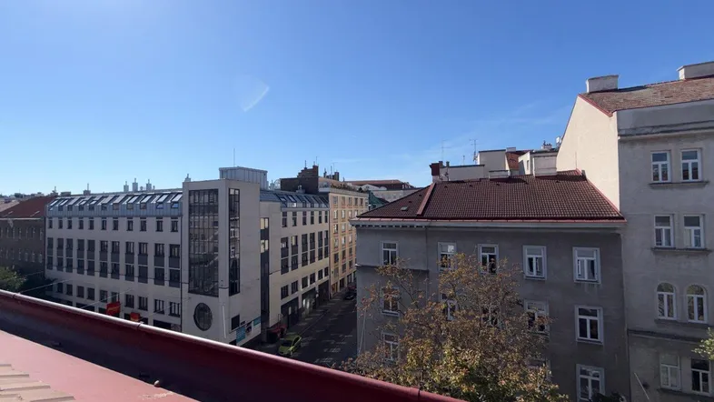 Blick über die Dächer einer Stadtstraße mit verschiedenen Gebäuden unter blauem Himmel.