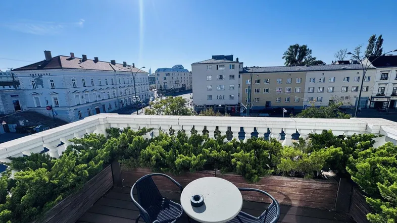 Eine sonnige Dachterrasse mit Sitzgelegenheiten und Blick auf die umliegende Stadtlandschaft.