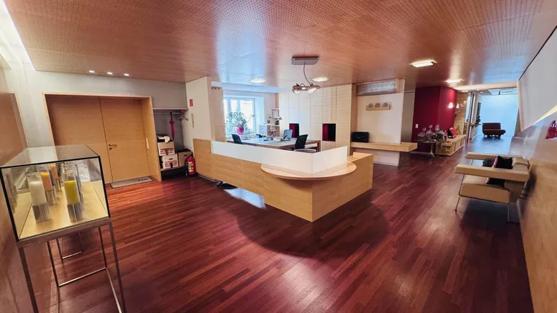 Geräumiger Empfangsbereich eines Büros mit Holzfußboden, Holzdecke und moderner Rezeption.