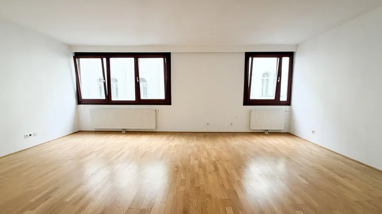 Helles, leeres Zimmer mit Parkettboden und weißen Wänden, bereit zur individuellen Gestaltung.