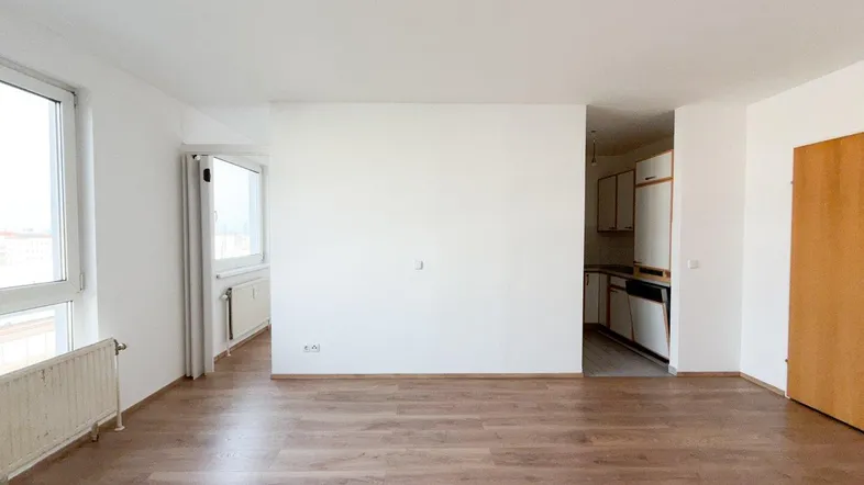 Heller, offener Wohnbereich mit Laminatboden und Zugang zu einem Küchenbereich.
