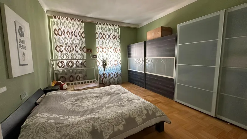 Gemütliches Schlafzimmer mit Parkettboden, grünen Wänden und großem Kleiderschrank.