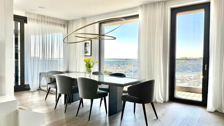 Heller Essbereich mit großem Esstisch, modernen Stühlen und weitem Ausblick durch bodentiefe Fenster.