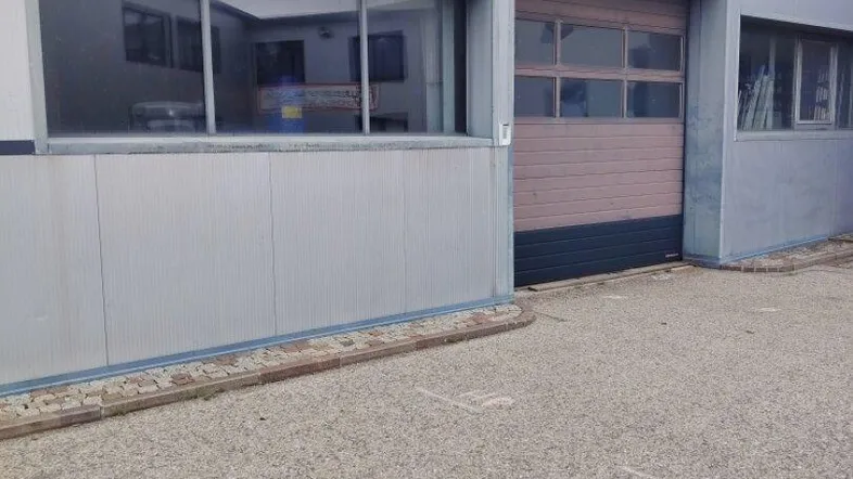 Außenansicht eines Gewerbegebäudes mit großer Rolltor-Einfahrt und Fenstern.