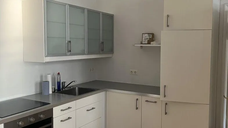 Helle Einbauküche mit modernen Schränken, Kochfeld und Backofen, ideal für den täglichen Gebrauch.