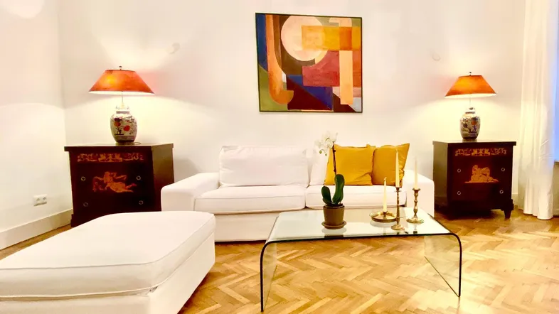 Gemütliches Wohnzimmer mit weißem Sofa, Beistelltischen und einem modernen Glastisch.