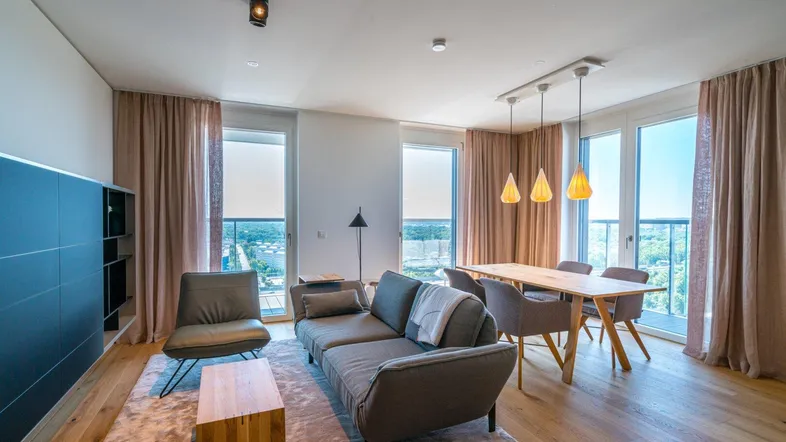 Helles, offenes Wohn-Esszimmer mit Holzboden, bequemen Möbeln und großen Fenstern mit Weitblick.