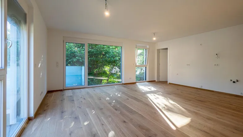 Helles und geräumiges Wohnzimmer mit großen Fenstern und Holzboden, bietet viel natürliches Licht.