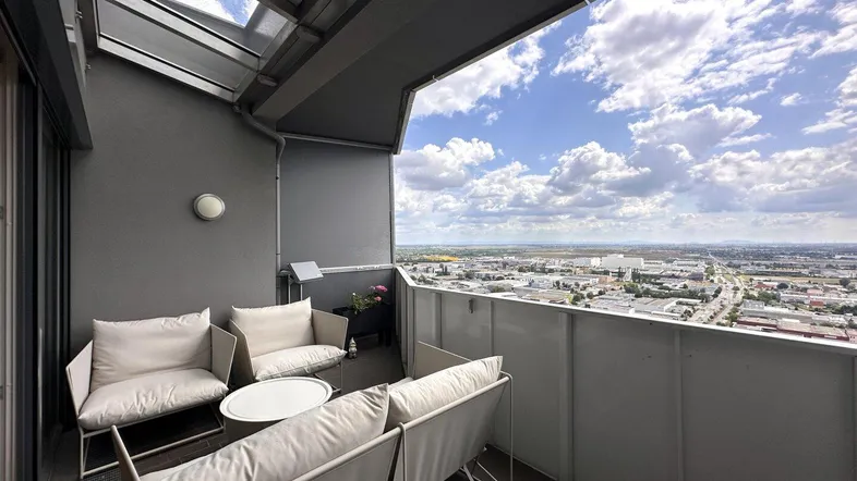 Geräumiger Balkon mit bequemen Sitzmöbeln und weitem Blick über die Stadtlandschaft.