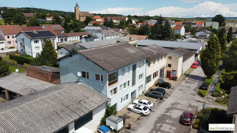 Luftaufnahme eines Wohn- und Geschäftshauses in einer ländlichen Umgebung mit umliegenden Gebäuden und Straßen.