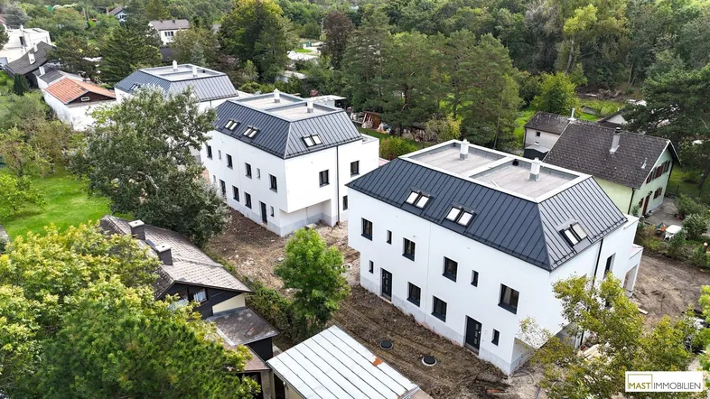 Luftaufnahme von mehreren modernen Neubauten in einer grünen, ländlichen Umgebung, noch im Bau.