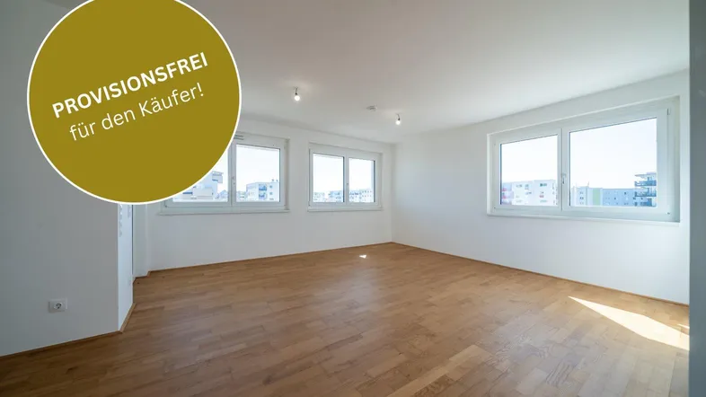 Heller, leerer Wohnraum mit neuem Parkettboden und großen Fenstern, die einen Blick auf die Stadt bieten.