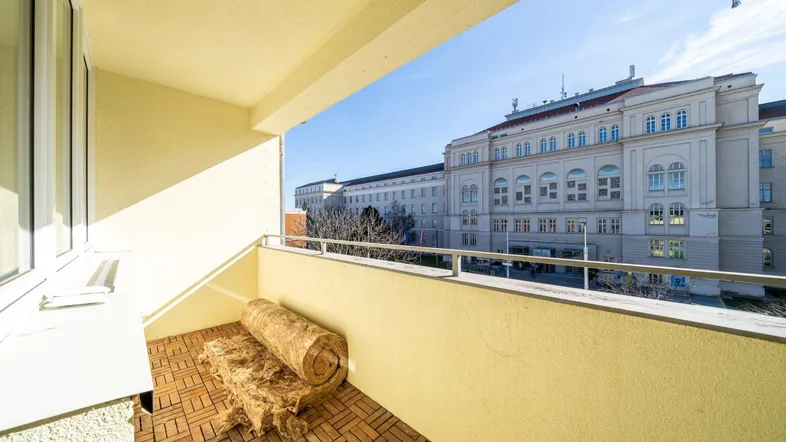 Geräumiger Balkon mit Holzboden und freiem Blick auf die umliegende Stadtarchitektur.