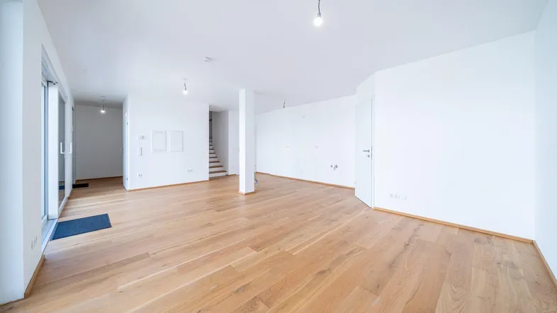 Heller, leerer Wohnbereich mit neuem Holzparkettboden und Zugang zur Terrasse.