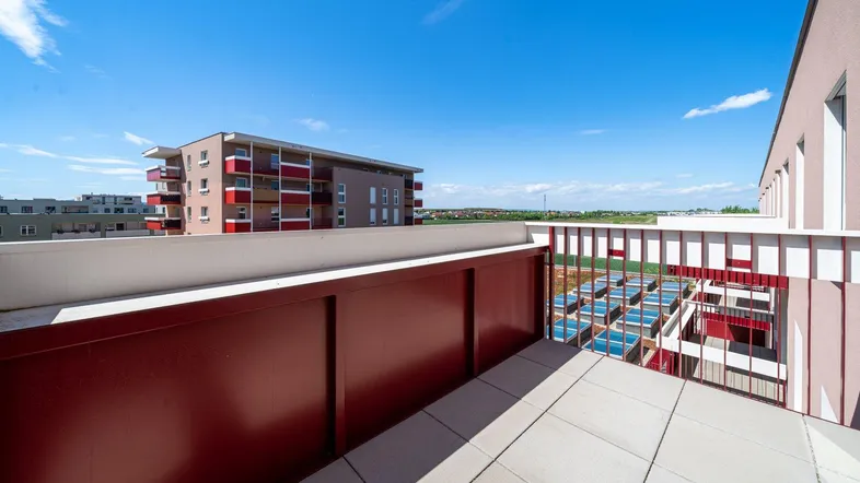 Balkon mit Fliesenboden und Blick auf umliegende Gebäude und die weite Landschaft.