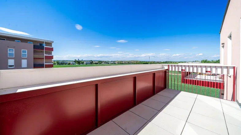 Geräumiger Balkon mit Fliesenboden und weitem Blick über die grüne Landschaft.