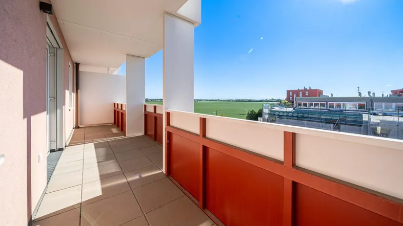 Heller Balkon mit Fliesenboden und weitem Blick über grüne Felder und die Umgebung.