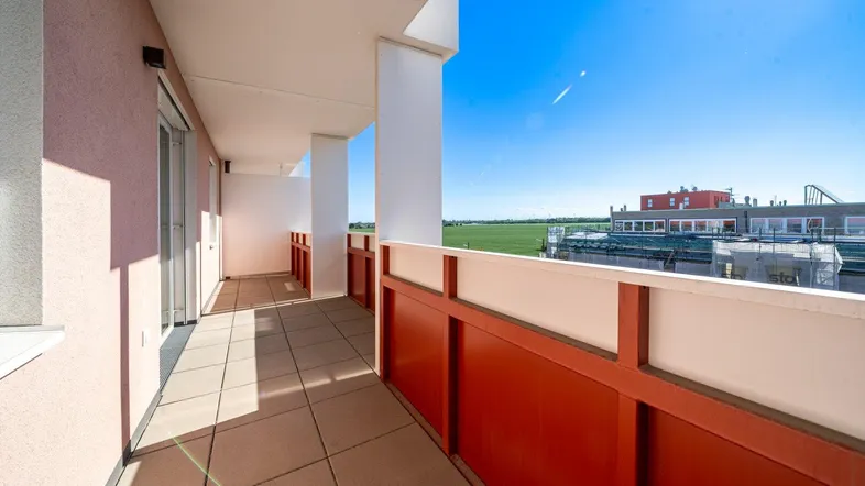 Geräumiger Balkon mit Fliesenboden und weitem Blick über grüne Felder und die Umgebung.