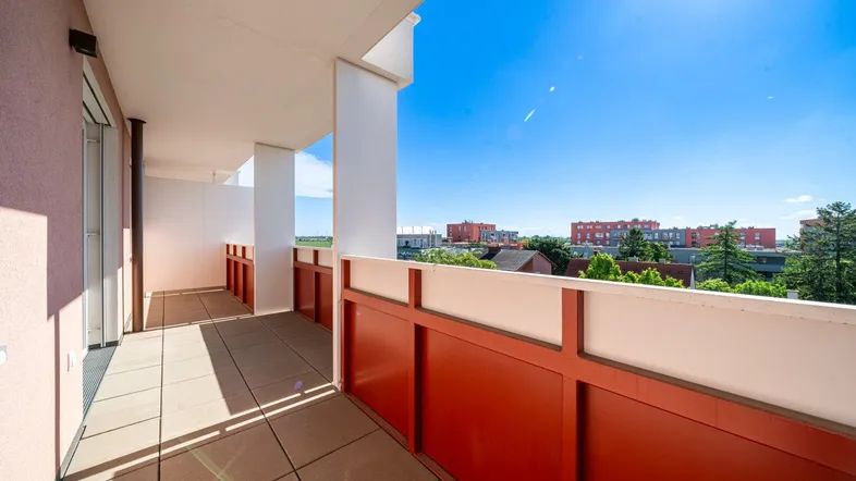Geräumiger Balkon mit Fliesenboden und weitem Blick über die Stadt bei Sonnenschein.