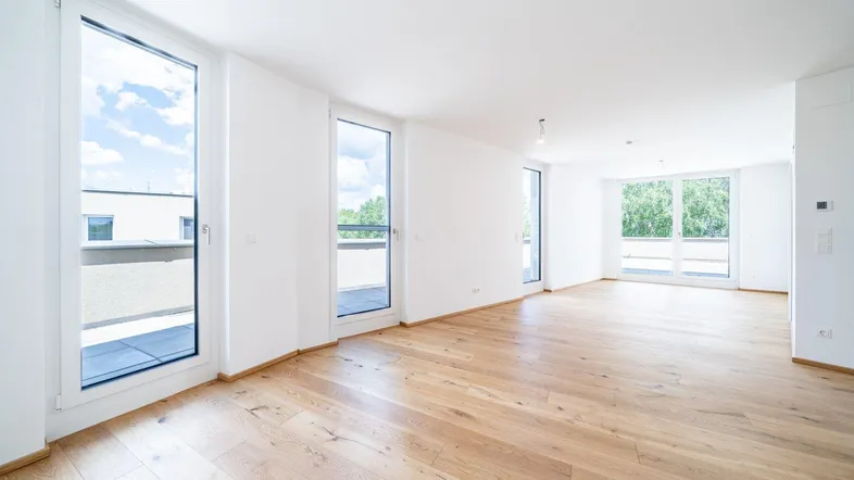 Helles, leeres Zimmer mit großen Fenstern und Holzboden, bereit zur individuellen Gestaltung.