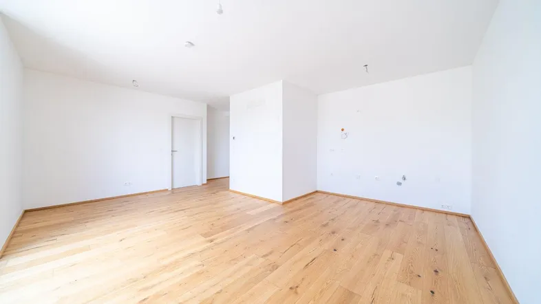 Helles, unmöbliertes Zimmer mit Holzboden und weißen Wänden, bereit zur individuellen Gestaltung.